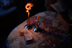 in the dark, a shabbat candle on a table is being lit with a match