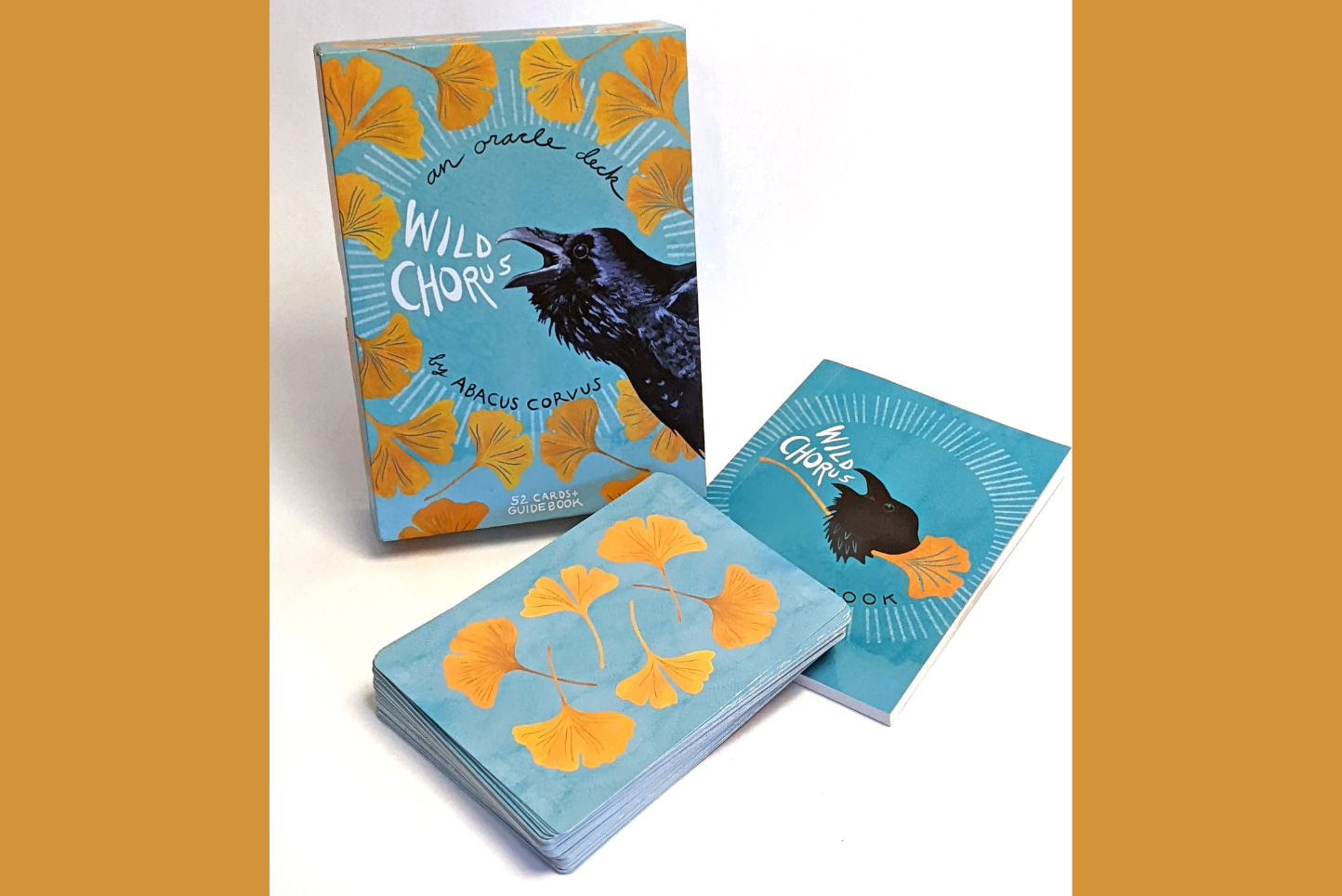 a cover, a deck and a guidebook with a raven and leaf motif and the text "wild chorus, an oracle deck by abacus corvus"