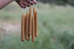 candles dangle from a hand with a green natural background