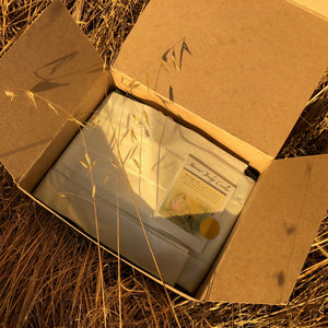 a box of wrapped candles sits on dry grass in the sun