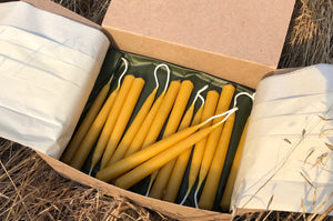 a box of beeswax candles on dried grass