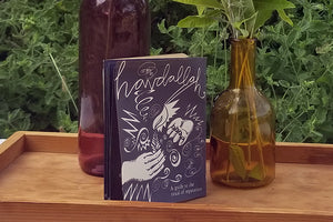 a book that reads "havdallah" on the cover with a design involving hands and squiggles, the book is on a table next to several bottles and herbs